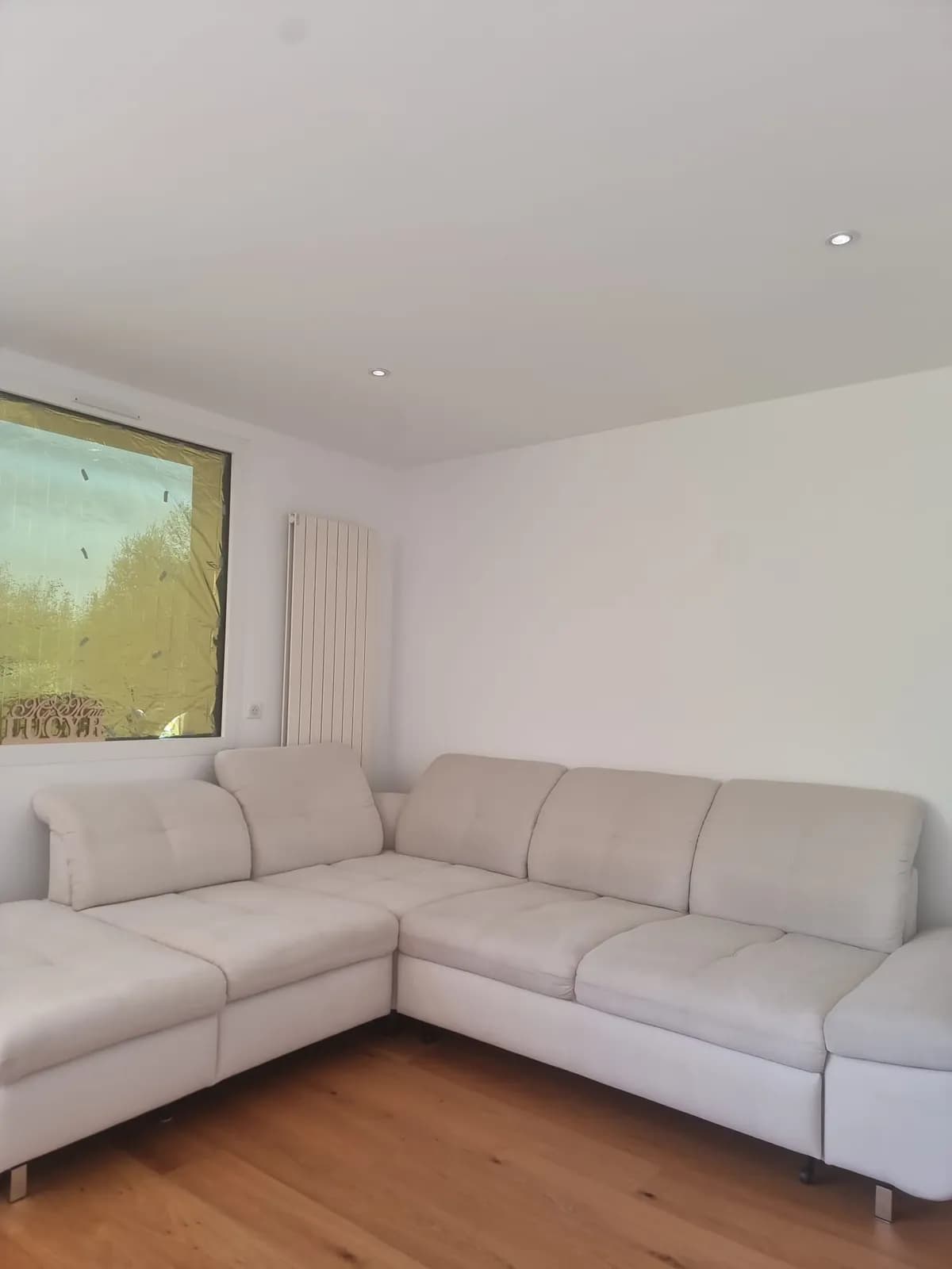 Canapé d'angle en tissu clair dans un salon, avant l'intervention