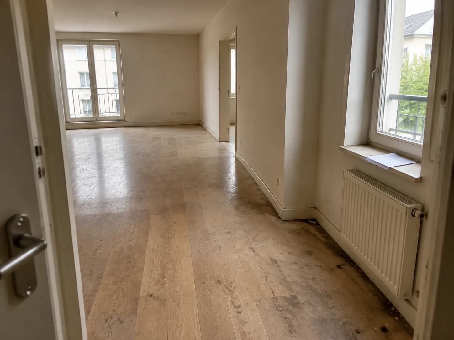 Logement vide avec une facture posée sur un appui de fenêtre, sol encore sale