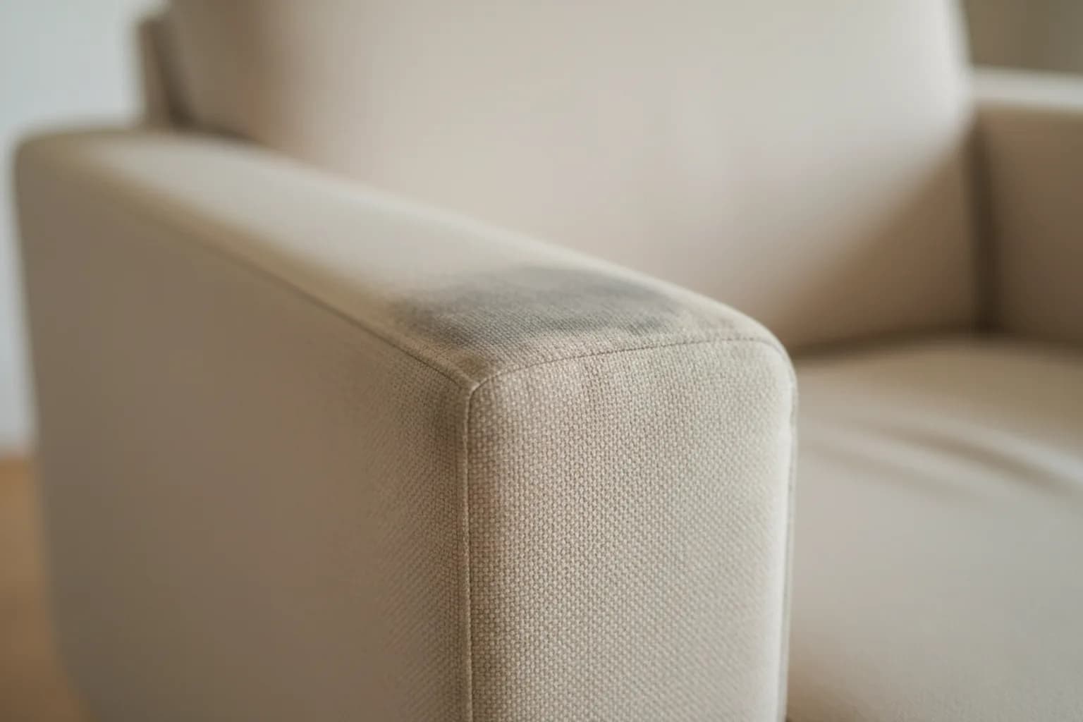 Accoudoir de fauteuil en tissu beige grisé et lustré par l'usage