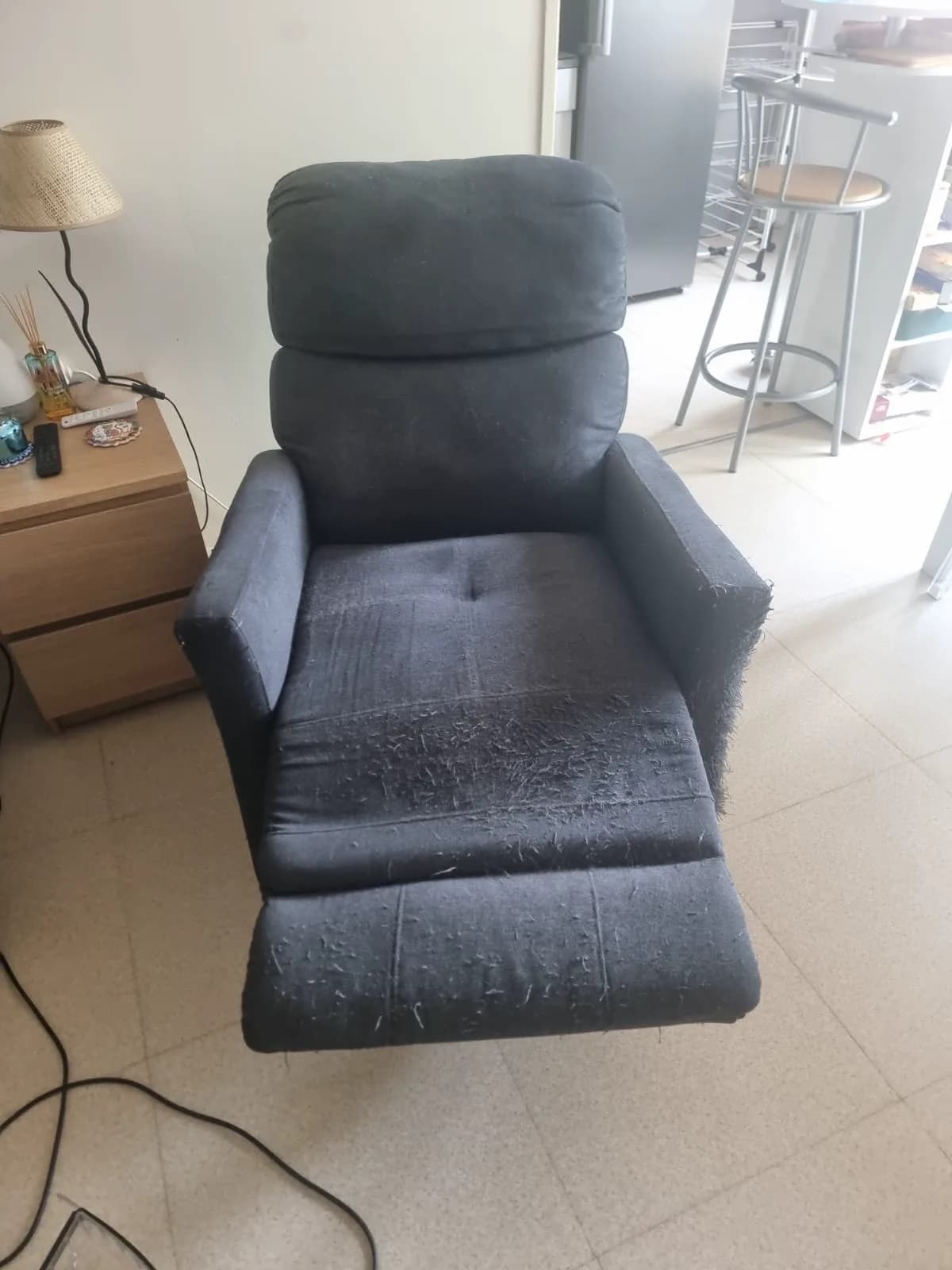 Fauteuil relax noir dont l'assise et le repose-jambes sont couverts de peluches et de poils clairs