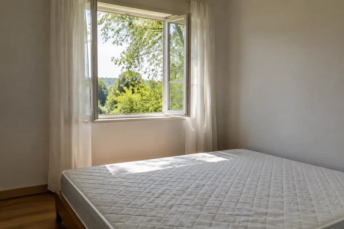 Chambre avec matelas nu et fenêtre ouverte