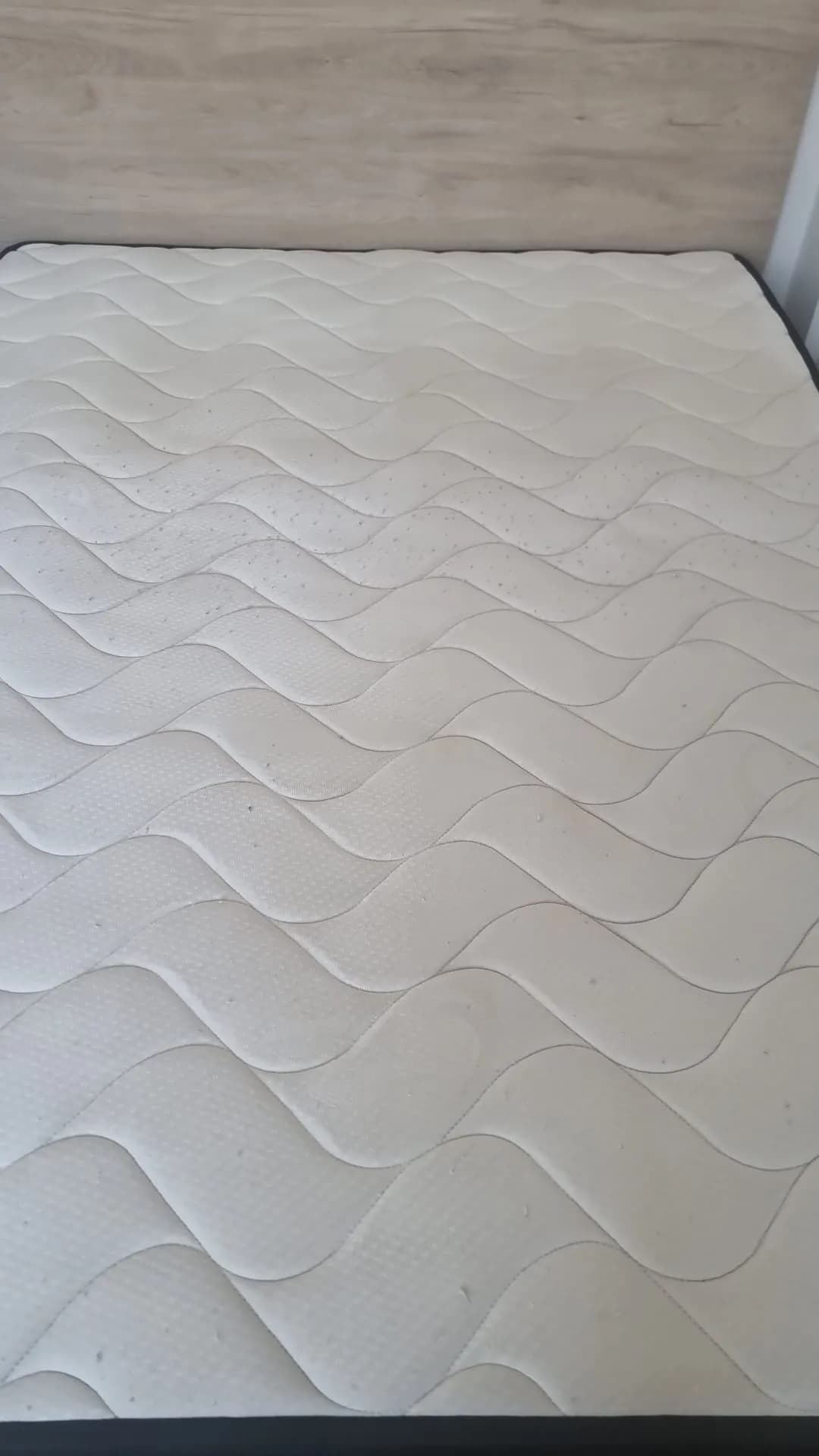 Matelas en cours de nettoyage : moitié haute piquée de points sombres, moitié basse nette